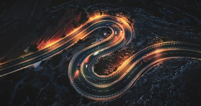 Malta: Aerial view winding road at night, with illuminated cars creating mesmerizing light trails against the dark landscape. Drone flight footage
