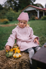 Young girl enjoying autumn at a pumpkin patch with colorful gourds in her hands