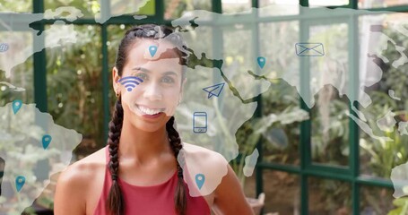 Woman standing in greenhouse starting world map overlay fading and populating global comms icons - Powered by Adobe