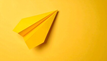 Bright yellow paper airplane on yellow background