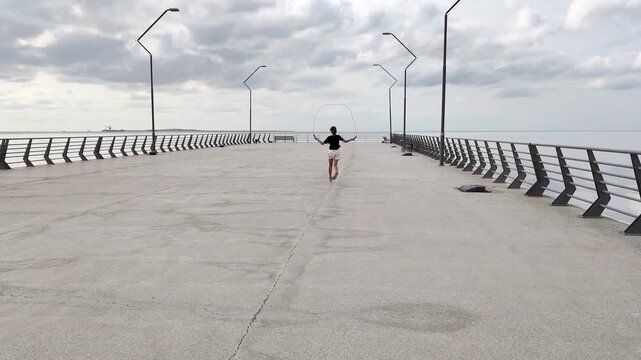 Teenage girl is jumping the robe on the seaside . High quality 4k footage