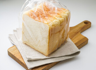 Sliced White Bread Loaf in a Bag on a Wooden Cutting Board side view of baked goods
