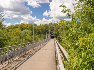 Scenic pedestrian bridge crossing lush green landscape under blue skies