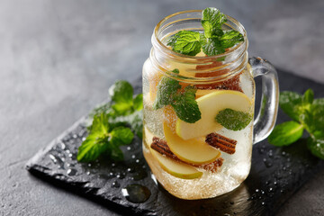 Mason Jar Infused Water with Apple Slices Cinnamon Sticks Fresh Mint on Dark Slate Tray