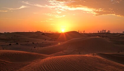 A vibrant desert sunset casts a golden glow over undulating sand dunes, with a distant cityscape silhouetted against the fiery sky