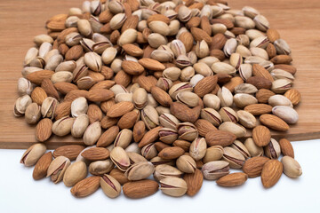 Assorted roasted almonds and pistachios heap on wooden table.