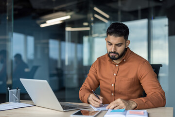 Professional businessman writing important notes in a notebook, concentrating on his work at a...