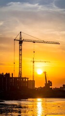 Construction cranes at sunset over water