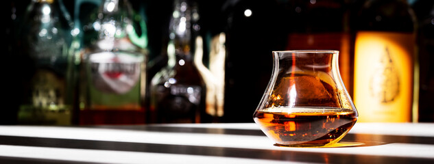 Bourbon or whiskey glass on dark green background with strong alcoholic drinks set. Spirits, liqueurs, distillates etc. in glasses and bottles