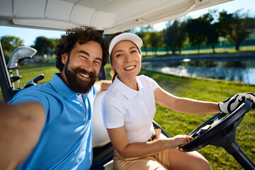 Happy golfers in buggy taking selfie and looking at camera.
