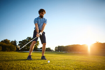 Below view of golf player taking first hit on course.