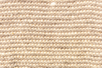 A close-up view of a textured fabric with a beige and cream color palette. The fabric features a woven pattern, creating a soft and inviting appearance.