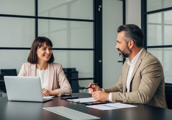 Fototapeta premium Professional business meeting with two colleagues discussing project strategy and planning on laptops in a modern office environment.