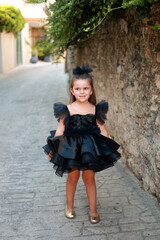 a little girl wearing a black dress like a model