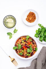 Mexican Chili con carne with beef, beans, corn, cilantro, jalapeno and tomato, white table background, top view