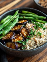 Delicious vegan rice bowl with roasted eggplant, green beans, and sesame sprinkled herbs served in a dark bowl on a wooden table