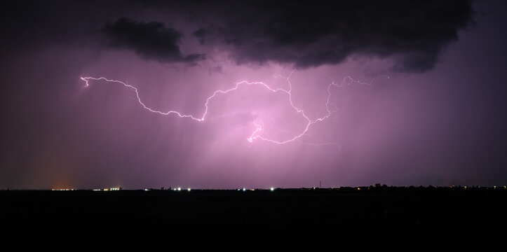 Dramatic night storm scene with purple lightning over the horizon, illuminating dark clouds  - Powered by Adobe