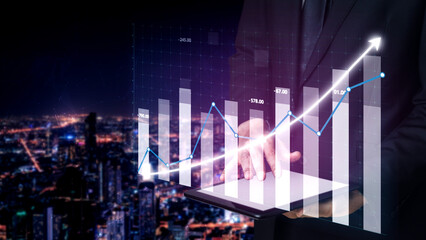 Fototapeta premium A businessman presents financial data on a digital tablet, showcasing growth trends against a night city backdrop, illustrating modern analytics. Impute