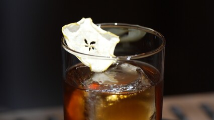 Closeup cocktail whiskey in Old fashioned with cube ice decorated dried sliced apple on top making special drink list, advertisement focusing alcohol refreshing showcase copy space at club. Vinosity.