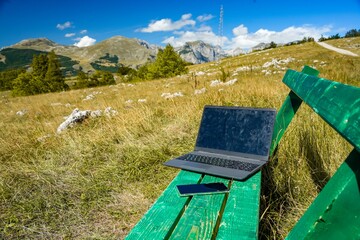 Medium shot of a laptop with a mobile phone on an outdoor bench in Montenegro