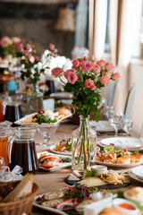 Elegant Wedding Reception Table Setting with Pink Roses. Food Platters, Glassware, and Rustic Decor in Warm Lighting