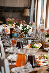 Elegant Wedding Reception Table Setting with Roses, Glassware, and Food Display, Warm Lighting and Rustic Charm