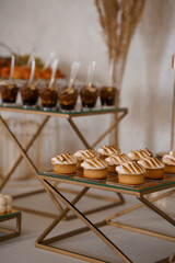 Elegant Dessert Table Display with Golden Accents and Sweet Treats for Weddings or Celebrations in Neutral Tones.