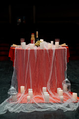Romantic Valentine's Day Table Setting with Candles, Wine, and Rose Red Decor on Dark Stage