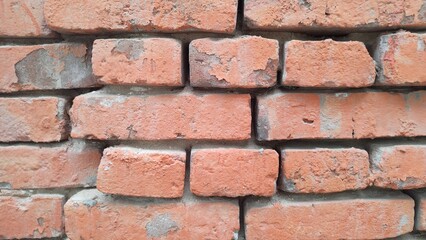 Close-up view of weathered red brick wall with visible signs of aging and wear, showcasing texture and imperfections of bricks and mortar