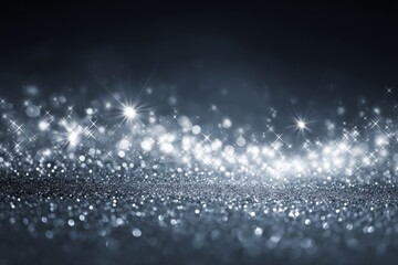 Sparkling glitter shines on a dark surface with many bokeh lights in the background.