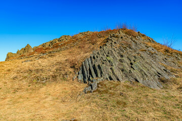 Scenic view of basalt rock formation with clear blue sky and grassy surroundings