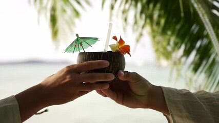 Coconut cocktail cheers by two people, holding refreshing tropical drinks garnished with umbrellas and exotic orchids, on a serene beach under swaying palm trees, embodying a blissful vacation.
