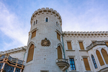 Historic white stone castle tower against blue sky with gothic architecture