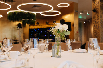 Elegant wedding table setup with white flowers and modern lighting in luxury restaurant