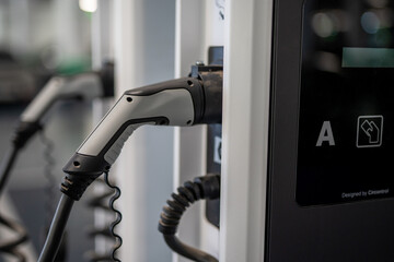 Close-up detail of electric vehicle charging plug inserted into station indoors