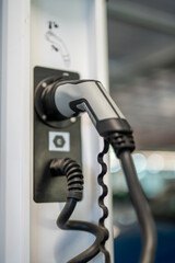 Detail of electric car charging plug connected to station indoors