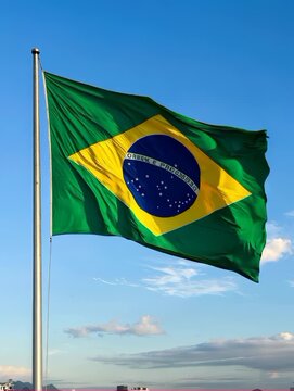 Brazilian flag waving slowly in the wind, clear blue sky background, vertical video, soft natural daylight.
