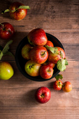 Freshly picked red apples on plate, rustic wooden background