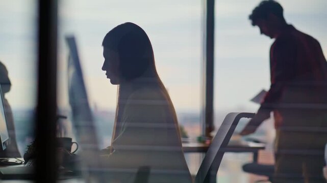 IT specialists silhouettes coding on computers in large coworking hub office