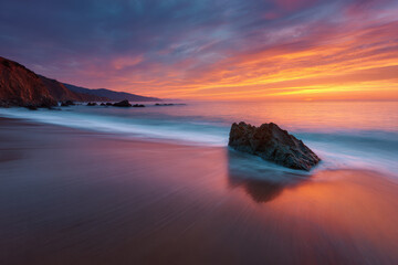 Obraz premium breathtaking sunset over ocean with solitary rock in foreground essence of tranquility