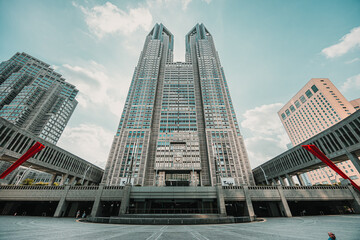 A low-angle, wide shot of the Tokyo Metropolitan Government Building, showcasing its distinctive twin towers and the modern, angular architecture