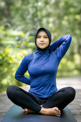 Young Indonesian Muslim girl performs yoga gymnastics sport in. Physical and mental exercises.