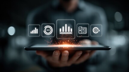 Human hand holding a tablet displaying glowing digital business and SEO icons