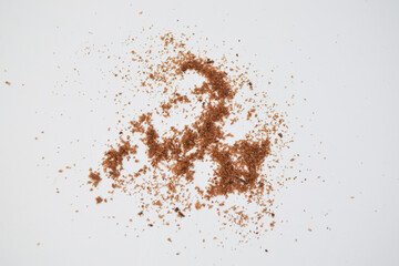 Brown chocolate crumbs scattered on a white background, showing texture and detail of sweet food ingredients