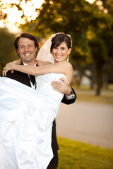 Happy Groom Carrying Bride in His Arms Outside - Romantic Wedding Moment