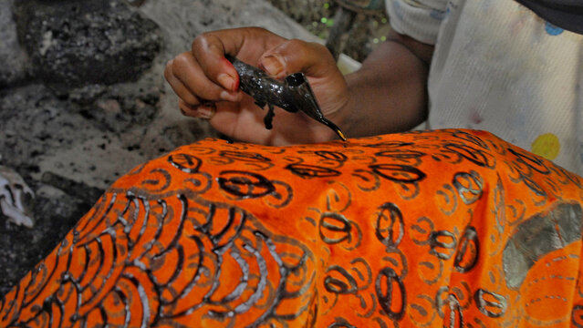 Close-up of artisan creating Indonesian Batik Tulis Madura using canting and hot wax. Traditional handmade textile craft, UNESCO cultural heritage, symbol of Hari Batik Nasional.