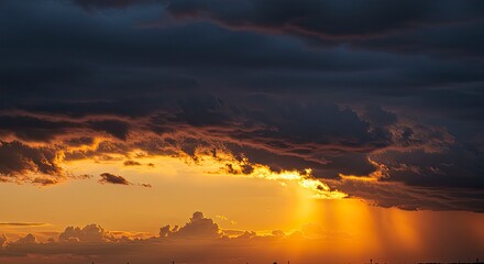 Obraz premium Dramatic Sunset Sky: Golden Light Piercing Through Stormy Clouds