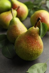 Fresh ripe pears and green leaves on grey table, closeup