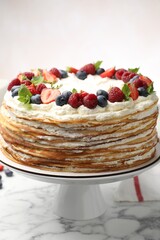 Delicious crepe cake with fresh berries on white marble table, closeup