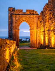 Fototapeta premium Golden sunset through ancient arches at a coastal ruins site near the sea